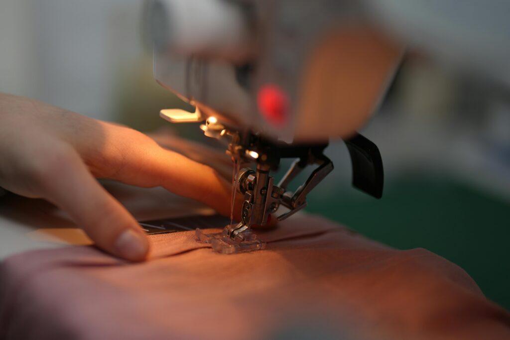 pexels-photo-11359034-11359034 Detailed view of a hand guiding fabric through a sewing machine in action.