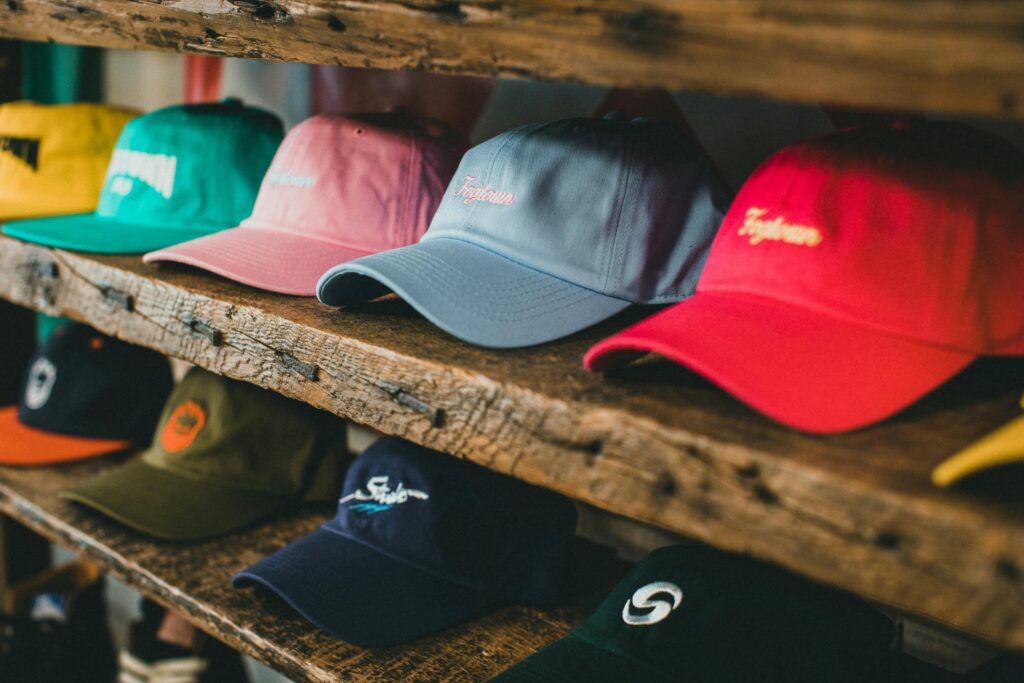pexels-photo-12284599-12284599 A variety of colorful baseball caps arranged on rustic wooden shelves in a store setting.
